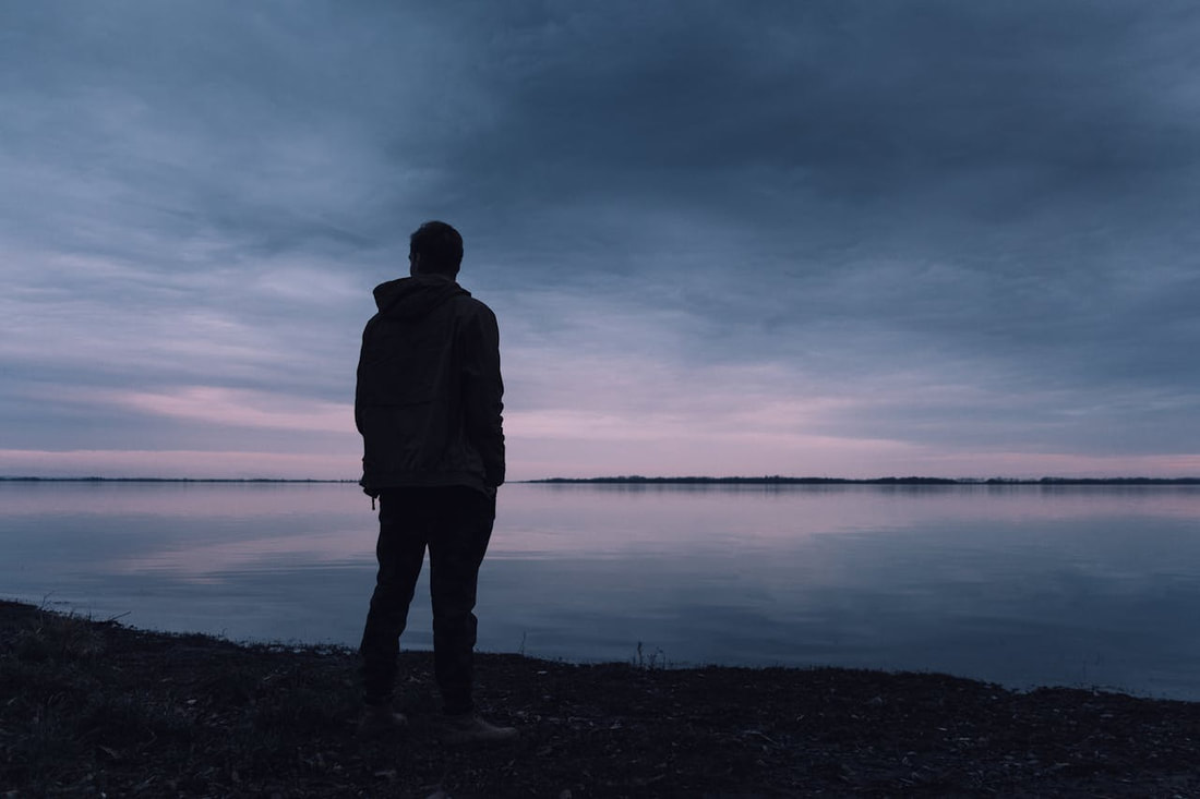 a man by the shore at night thinking about how alcohol use can exacerbate mental  health symptoms